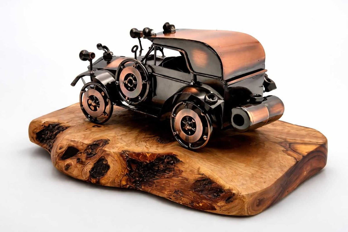 Artisan metal vintage car olive wood sculpture on a natural wooden base against white background.