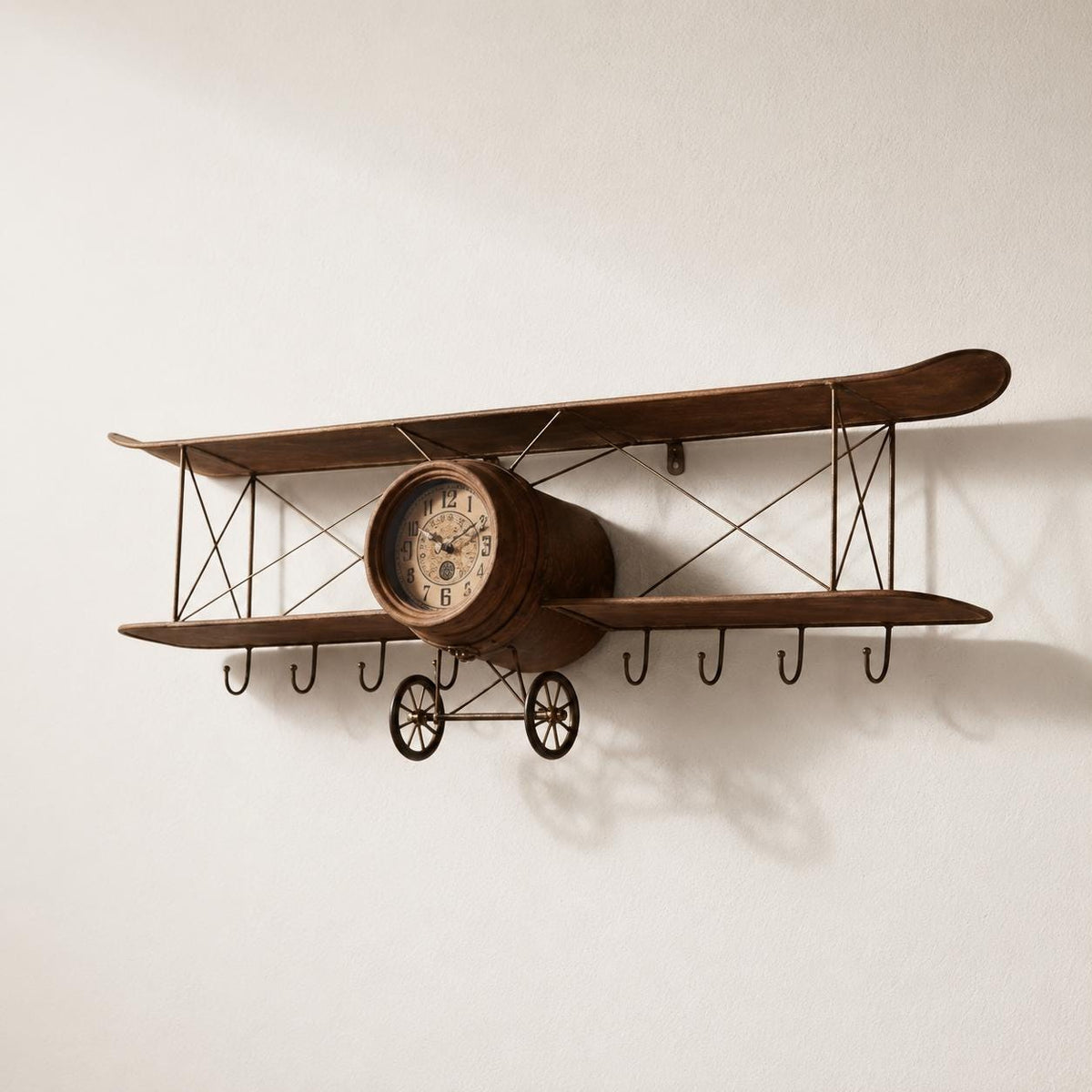 Angled studio view of a biplane model vintage airplane olive wood wall clock on white.