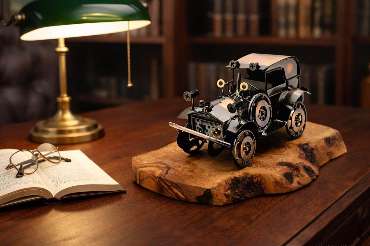 Metal vintage car olive wood sculpture displayed on an office desk under warm lamp light.