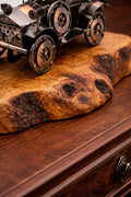 Side angle view of a rustic metal vintage car olive wood sculpture on a polished table.